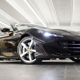 Black Ferrari Portofino with headlights on
